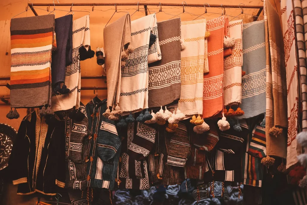 Striped woven blankets and textiles hanging at a market stall in Agadir