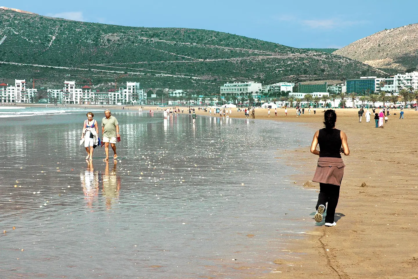 People walking on Agadir beach with the seafront and the Kasbah hill behind