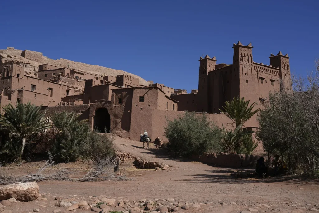 Mud-brick kasbah towers and walls in the Ouarzazate region under a blue sky