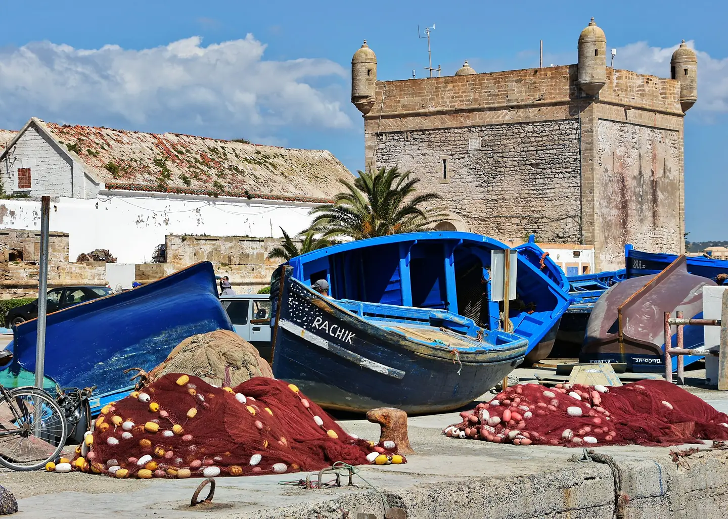 Blue fishing boats and red nets in Essaouira port below the Skala fort
