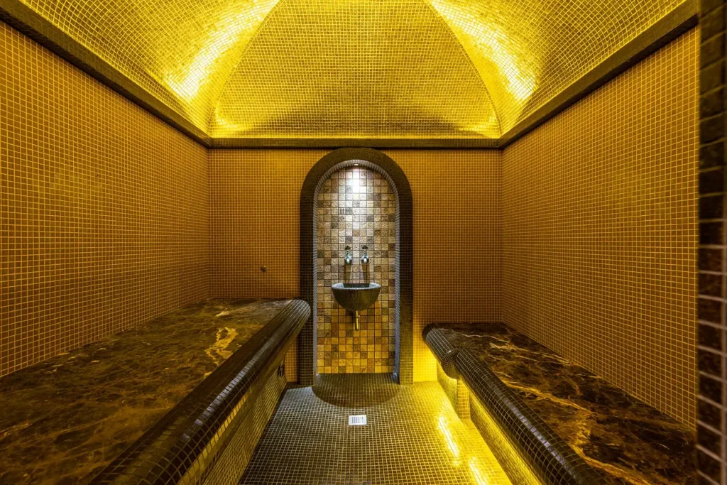 Steam room of a hammam with gold mosaic walls and marble benches