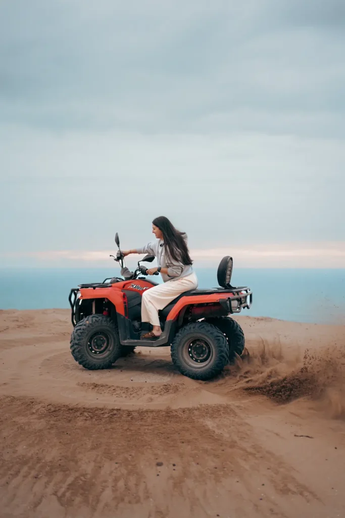 Red quad bike on the edge of a dune with the ocean below