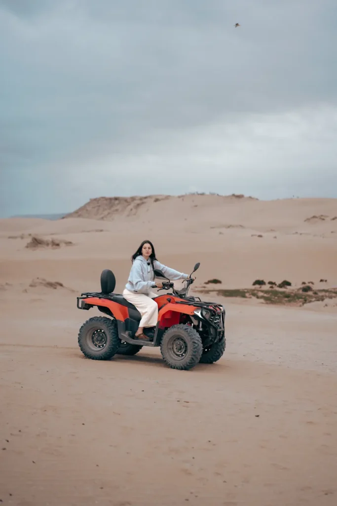 Rider on a red quad bike among sand dunes