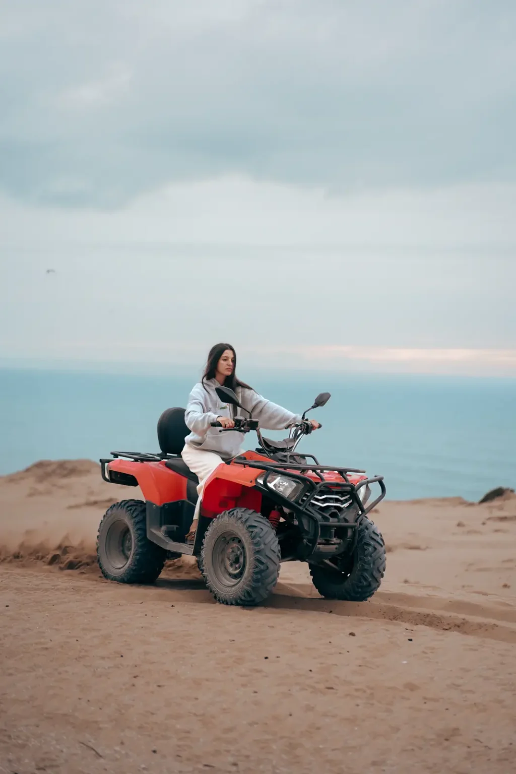 Rider on a red quad bike on a dune above the Atlantic