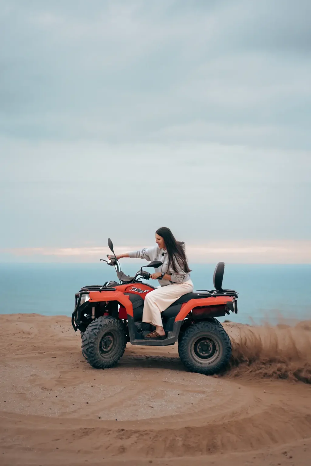 Quad bike turning on the sand with the ocean behind